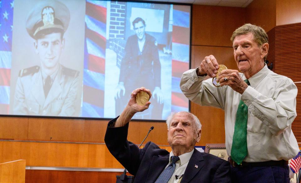 Bill Pruitt, 102, and Ed Trester, 95,  show the crowd gathered in the auditorium of the St. Johns County Administration building in St. Augustine their Congressional Gold Medals after a presentation ceremony on Thursday, June 30, 2022.