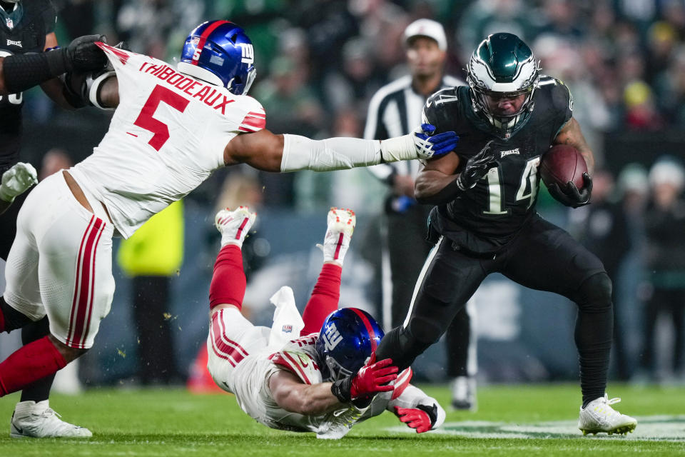 Philadelphia Eagles running back Kenneth Gainwell runs past New York Giants linebacker Kayvon Thibodeaux (5) and linebacker Micah McFadden during the second half of an NFL football game Monday, Dec. 25, 2023, in Philadelphia. (AP Photo/Matt Slocum)