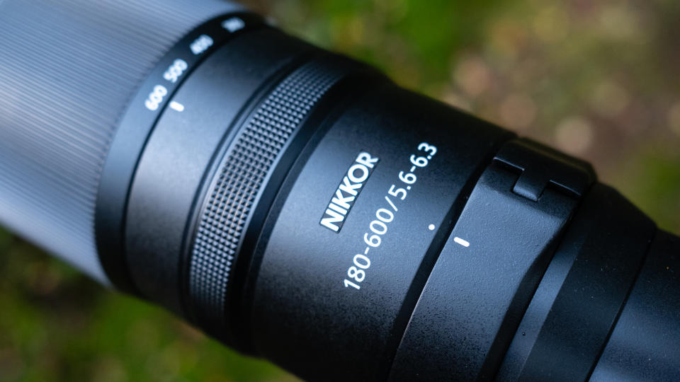 Close up photos of the Nikkor Z 180-600mm f/5.6-6.3 VR mounted on a tripod with foliage in the background