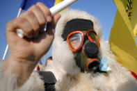 An anti-vaccination protester wears a gas mask during a rally outside the parliament building in Bucharest, Romania, Sunday, March 7, 2021. Some thousands of anti-vaccination protestors from across Romania converged outside the parliament building protesting against government pandemic control measures as authorities announced new restrictions amid a rise of COVID-19 infections. (AP Photo/Vadim Ghirda)