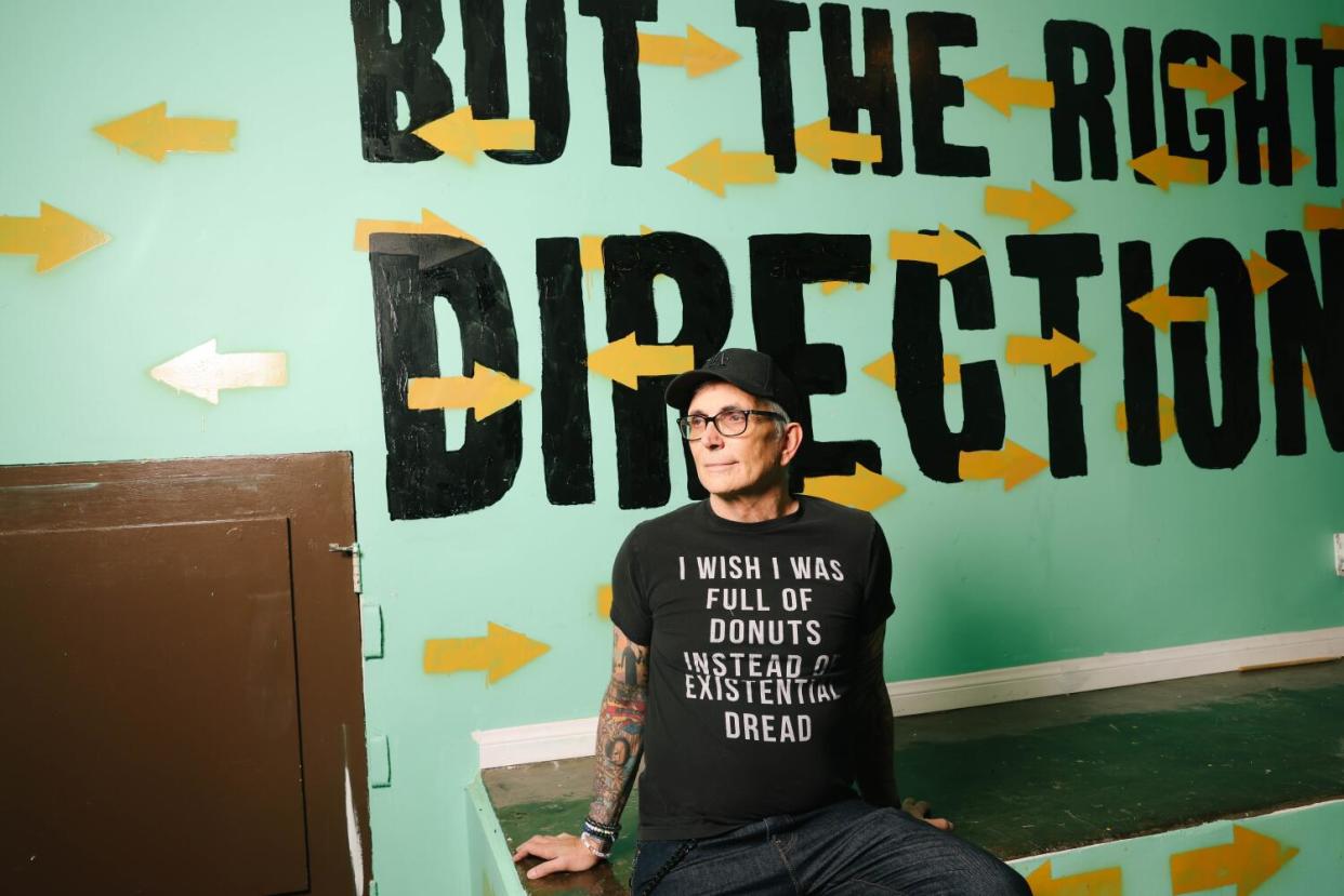 Man in black t-shirt sitting in front of blue wall mural