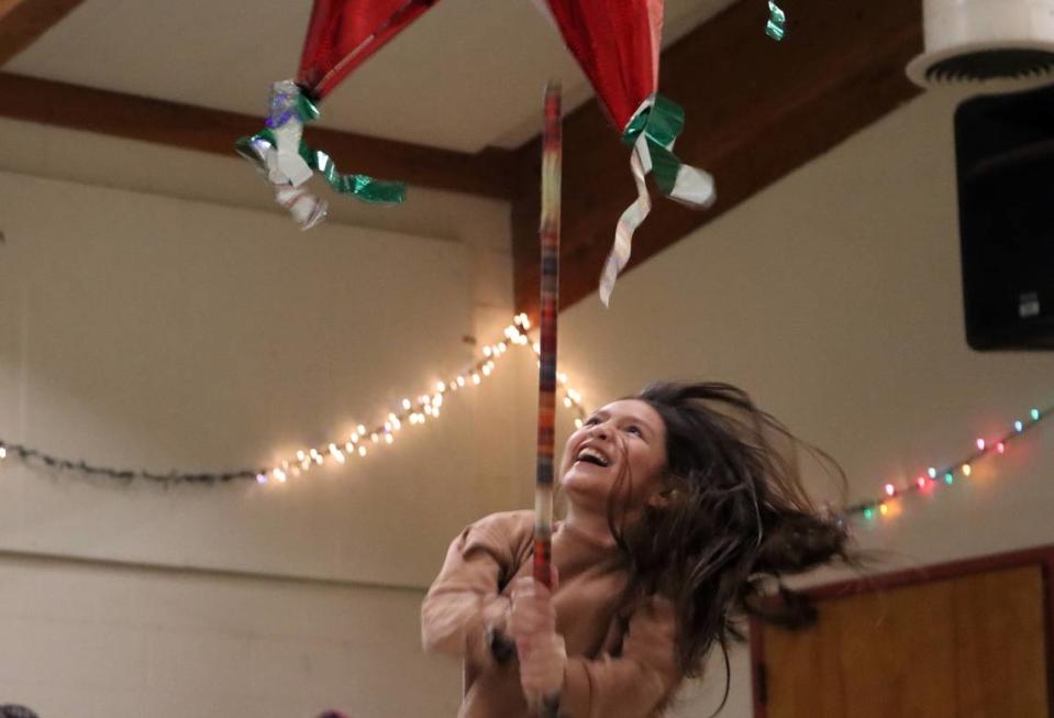 Una niña golpea una piñata durante la posada organizada por la Iglesia de San Antonio María Claret en el sureste de Fresno, el 18 de diciembre de 2023.