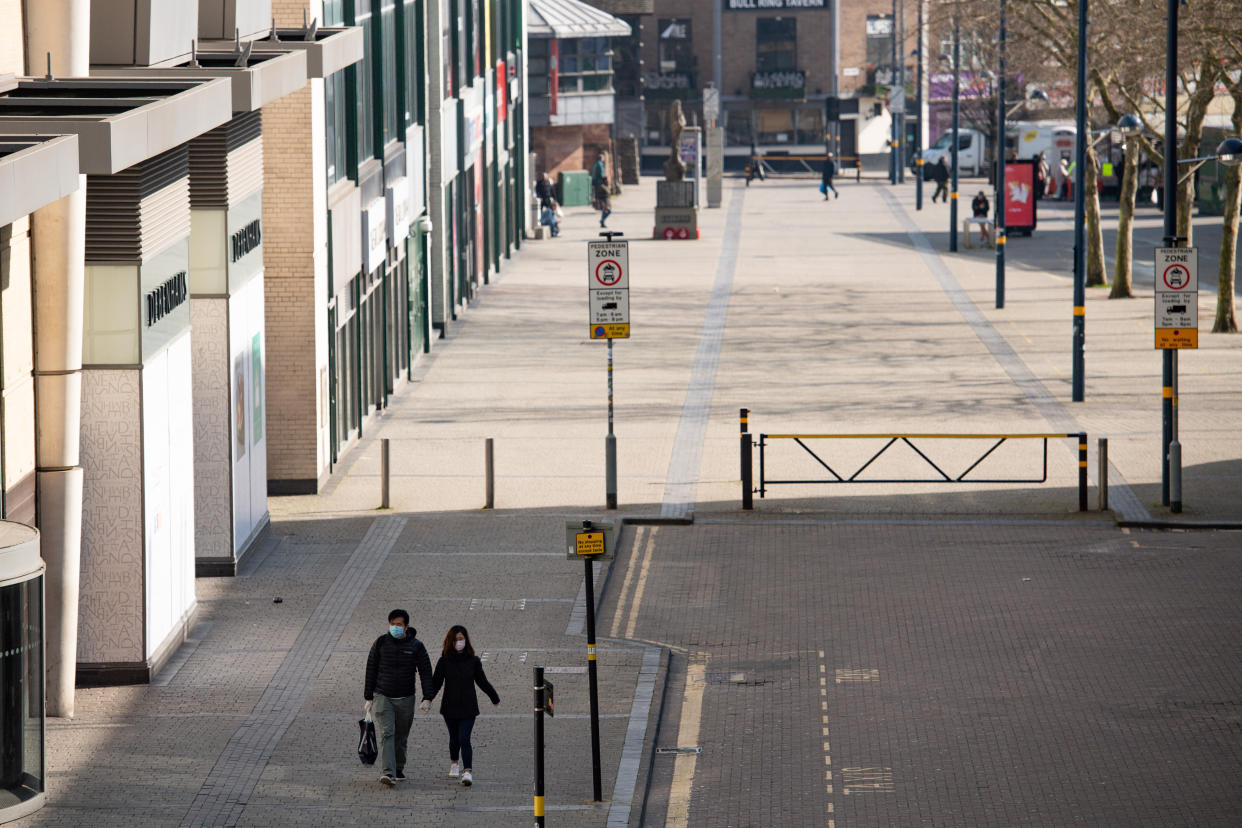 A couple wearing protevtive equipment walk by the Bullring in Birmingham, the day after Prime Minister Boris Johnson put the UK in lockdown to help curb the spread of the coronavirus.