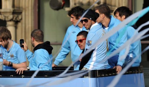 Manchester City's Argentinian forward Carlos Tevez (C, black hat) sits with his teammates on an open topped bus as they celebrate becoming English Premier League champions in a parade in Manchester. Tevez landed himself in fresh controversy on Monday when he was pictured waving a mocked-up tombstone for Sir Alex Ferguson during Manchester City's Premier League title celebrations