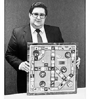 Buffalo inventor Charles P. Marino holds the board for one of his Great Blizzard games.