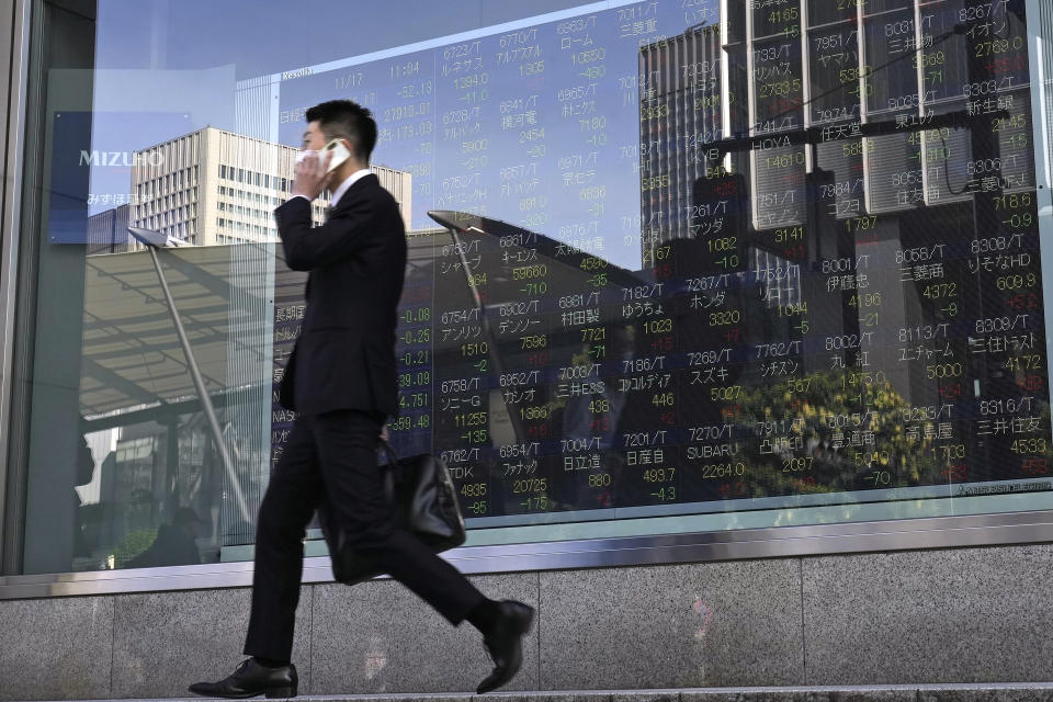 A person walks in front of an electronic stock board showing Japan's Nikkei 225 index, center left, at a securities firm Thursday, Nov. 17, 2022, in Tokyo. Asian shares mostly declined Thursday amid concerns about the impact of China's "zero-COVID" strategy mixed with hopes for economic activity and tourism returning to normal. (AP Photo/Shuji Kajiyama)