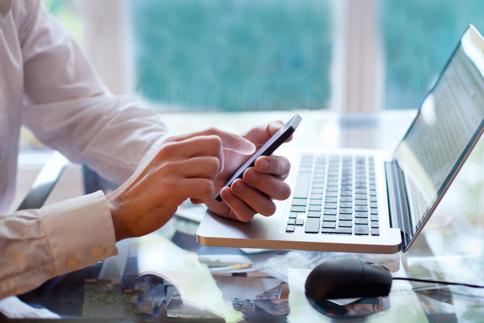 Man at laptop checking cell phone