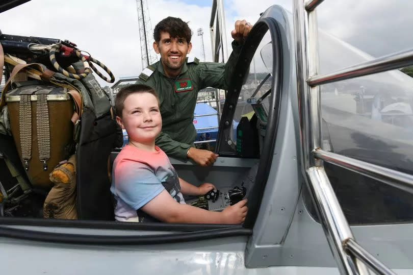 Boy sat in aircraft with airman stood nearby