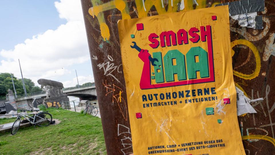 Ein gelbes Plakat mit der Aufschrift «Smash IAA Autokonzerne entmachten und enteignen!» klebt an einer Wand in der Stadt.