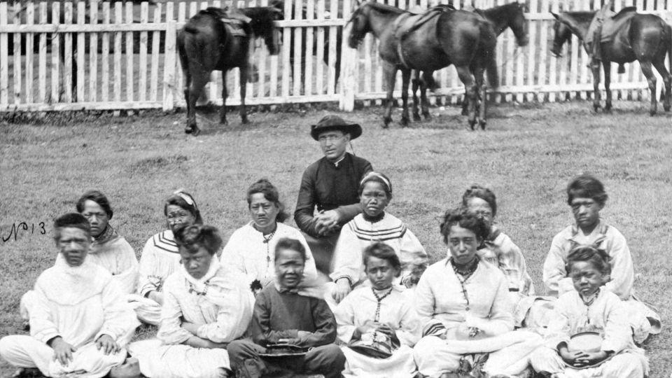 Father Damien is pictured with the Kalawao Girls Choir, circa 1878. Kalawao is a settlement on the Kalaupapa Peninsula. - Alamy Stock Photo