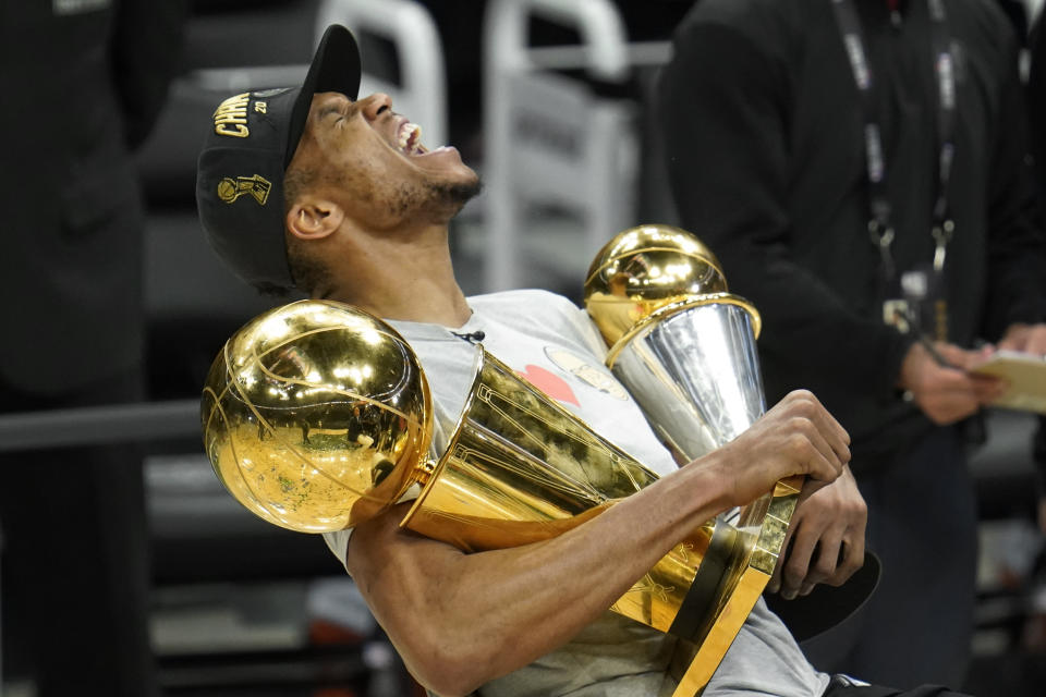 FILE - Milwaukee Bucks forward Giannis Antetokounmpo reacts while holding the NBA Championship trophy, left, and Most Valuable Player trophy after defeating the Phoenix Suns in Game 6 of basketball's NBA Finals in Milwaukee, Tuesday, July 20, 2021. The Bucks won 105-98. (AP Photo/Paul Sancya, File)