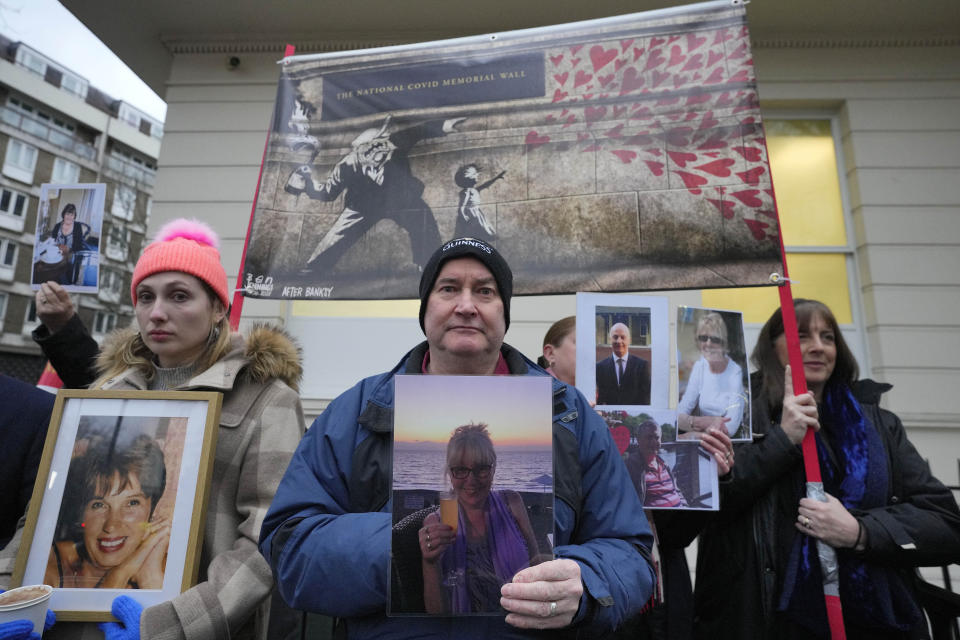 Protesters show pictures of COVID victims outside Dorland House as Britain's former Prime Minister Boris Johnson testifies at Britain's COVID-19 public inquiry in London, Thursday, Dec. 7, 2023. (AP Photo/Kirsty Wigglesworth)