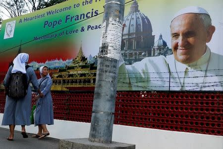 Two catholic nuns walk past a banner welcoming Pope Francis, ahead of his visit to Myanmar, in Yangon, Myanmar November 26, 2017. REUTERS/Jorge Silva