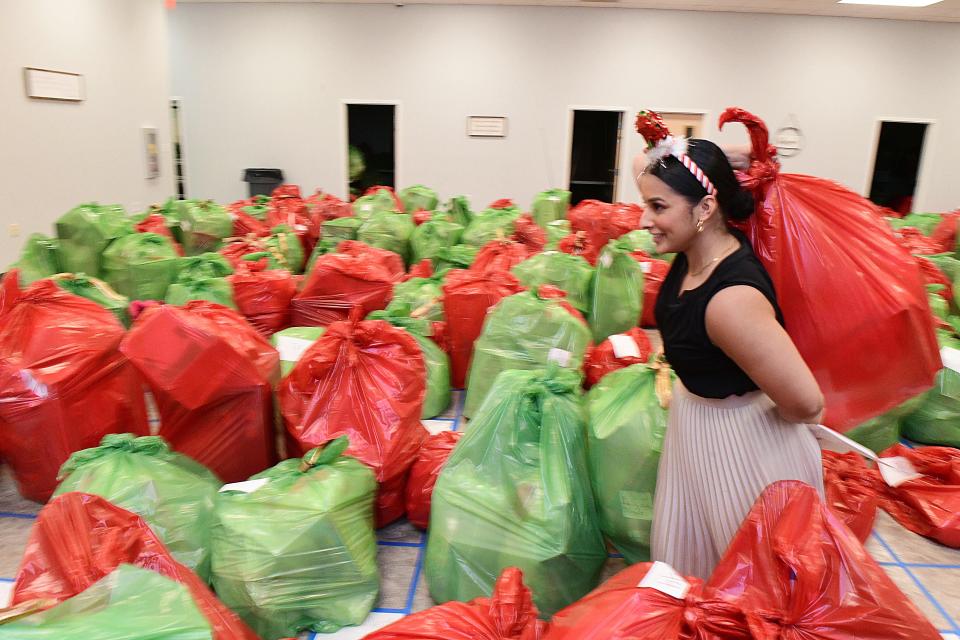 Kaylah Acosta with Catholic Charities carries a bag of toys Thursday as she and other volunteers help distribute Christmas items through the Salvation Army Angel Tree program. Working with Catholic Charities, the Salvation Army Angel Tree program will help bring Christmas to more than 800 children this year.