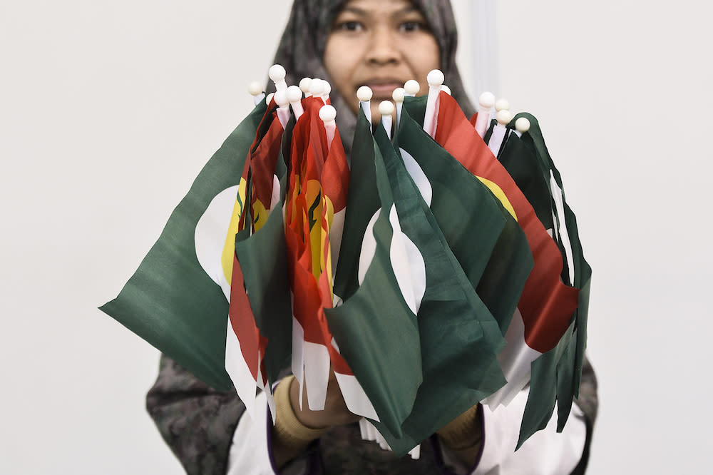 A woman holds PAS-Umno flags during Himpunan Penyatuan Ummah (Muslim Unity Rally) at Putra World Trade Centre in Kuala Lumpur September 13, 2019. — Picture by Miera Zulyana