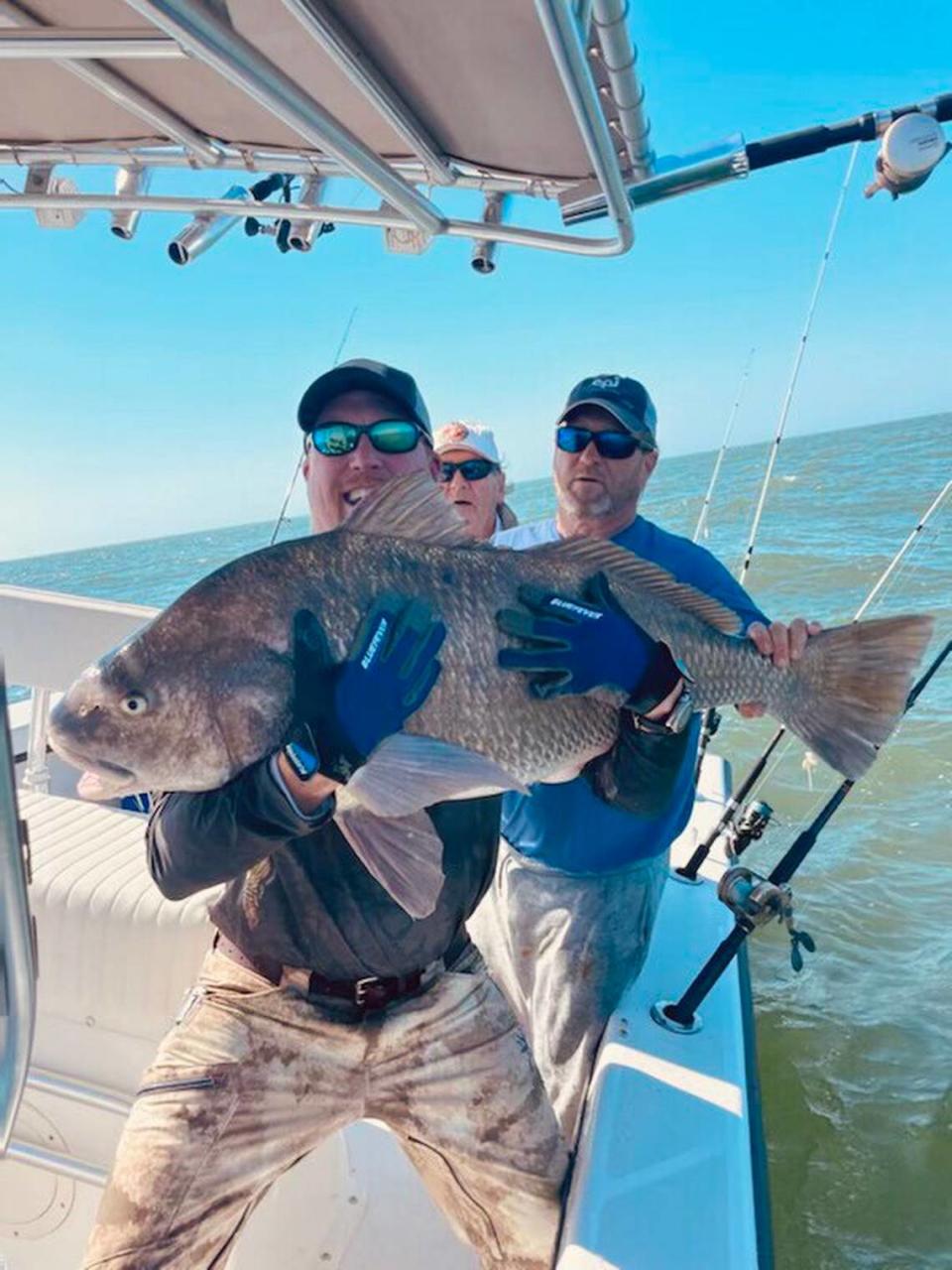 Micah Young of Florence hoists a huge black drum caught out of Georgetown with his brother, Kevin Young, and father, John Young, looking on.