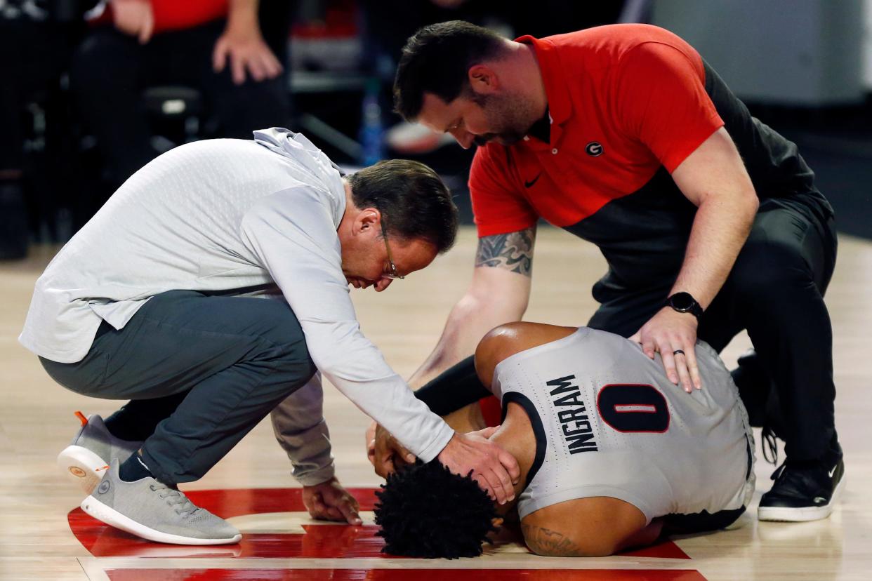 Georgia coach Tom Crean checks on Georgia's Jailyn Ingram (0) after he went down with an injury during a basketball game between Jacksonville and Georgia in Athens, Ga., on Tuesday, Dec. 7, 2021. Georgia won 69-58.