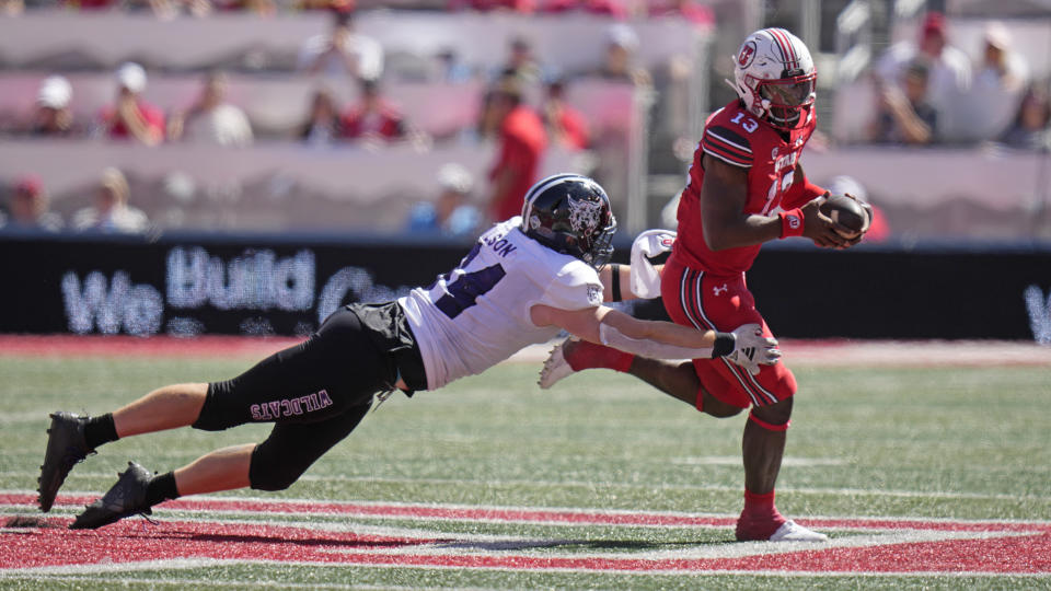 Utah quarterback Nate Johnson (13) breaks free from Weber State defensive end Brayden Wilson (94) tackle during the second half of an NCAA college football game Saturday, Sept. 16, 2023, in Salt Lake City. (AP Photo/Rick Bowmer)