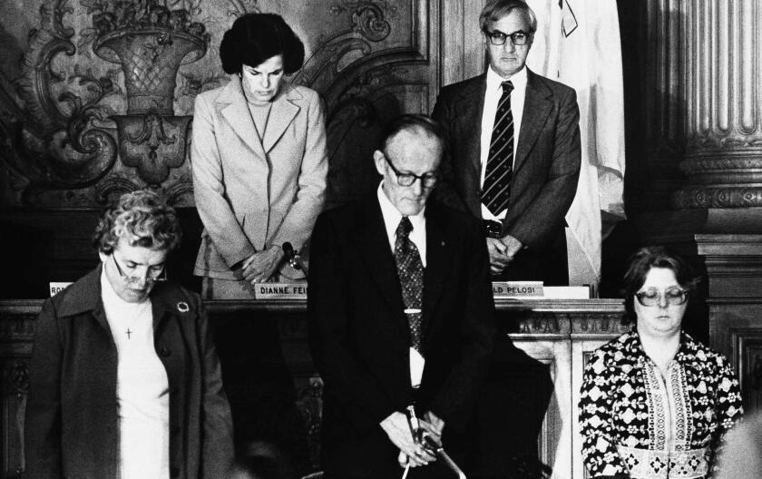 The San Francisco Board of Supervisors, presided over by president and now acting Mayor Dianne Feinstein, top left, bow their heads in silence for Mayor George Moscone and Supervisor Harvey Milk who were shot to death at City Hall in San Francisco, Nov. 27, 1978. Others are unidentified. (AP Photo/A. Cope)