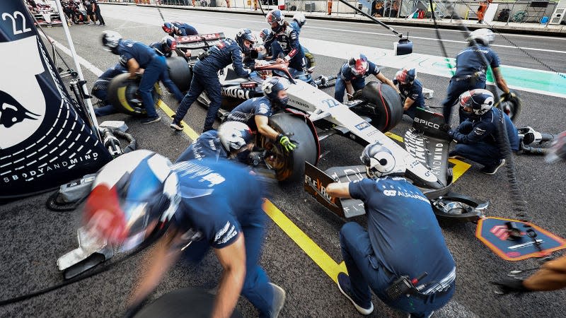 A photo of mechanics changing the wheels on an Alpha Tauri F1 car. 