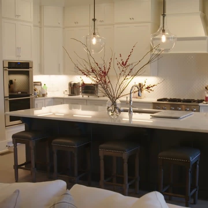 The kitchen is next to the living room and it is all white with an island