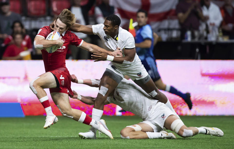 Canada's Brennig Prevost, left, is tackled by United States' David Still, front right, and Joe Schroeder during an HSBC Canada Sevens rugby game in Vancouver, British Columbia, Saturday, Sept. 18, 2021. (Darryl Dyck/The Canadian Press via AP)