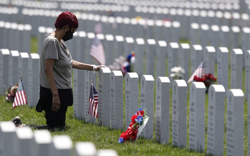 Cleveland resident Rosemay Thomas touches the tombstone of her husband at the Ohio Western Reserve National Cemetery on Memorial Day in Seville