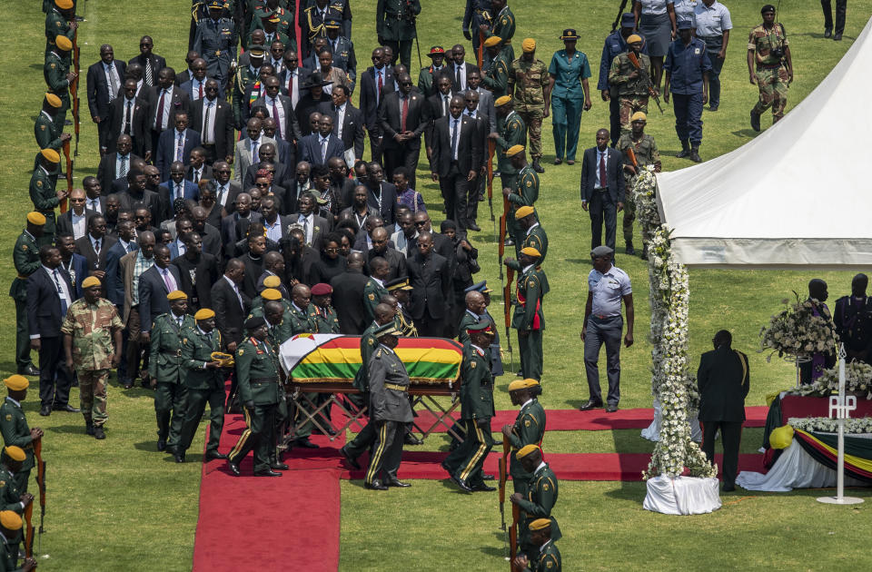 The casket of former president Robert Mugabe, covered by the national flag and followed by family and dignitaries, arrives for a state funeral at the National Sports Stadium in the capital Harare, Zimbabwe Saturday, Sept. 14, 2019. African heads of state and envoys are gathering to attend a state funeral for Mugabe, whose burial has been delayed for at least a month until a special mausoleum can be built for his remains. (AP Photo/Ben Curtis)