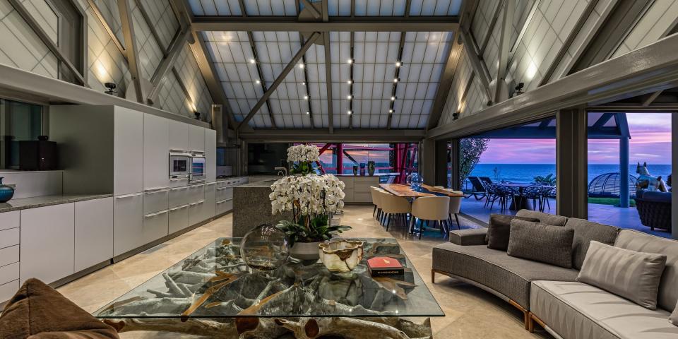 A grey open plan kitchen and living room during sunset.