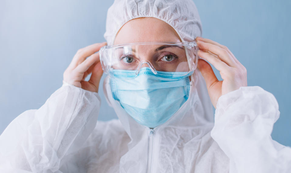 Female doctor puts on safety glasses, close-up of face.