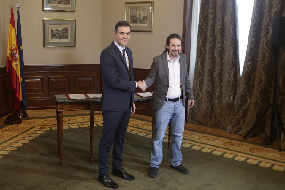 Spain's caretaker Prime Minister Pedro Sanchez, left, and Podemos party leader Pablo Iglesias shake hands before signing an agreement at the parliament in Madrid, Spain, Tuesday, Nov. 12, 2019. The leaders of Spain's Socialist party and the left-wing United We Can (Podemos) party say they have reached a preliminary agreement toward forming a coalition government. But the deal announced Tuesday won't provide enough votes in parliament for the Socialists, who won a general election, to take office without the support of other parties. (AP Photo/Paul White)