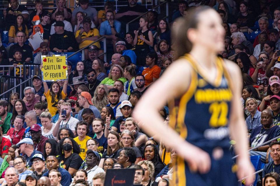 A fan holds up a sign saying ‘I’ve got Caitlin Fever,’ while Indiana Fever guard Caitlin Clark (22) shoots a free throw in the fourth quarter of a WNBA preseason game between the Dallas Wings and Indiana Fever at College Park Center in Arlington on Friday, May 3, 2024.