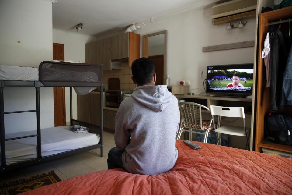 An Afghan father watches television in his room, at the port of Vathy on the eastern Aegean island of Samos, Greece, Wednesday, Feb. 24, 2021. On a hill above a small island village, the sparkling blue of the Aegean just visible through the pine trees, lies a boy’s grave. His first ever boat ride was to be his last - the sea claimed him before his sixth birthday. His 25-year-old father, like so many before him, had hoped for a better life in Europe, far from the violence of his native Afghanistan. But his dreams were dashed on the rocks of Samos, a picturesque Greek island almost touching the Turkish coast. Still devastated from losing his only child, the father has now found himself charged with a felony count of child endangerment. (AP Photo/Thanassis Stavrakis)