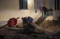 People remove mud from in front of a flooded house after heavy rainfall triggered landslides that collapsed buildings and left as many as 12 people missing, in Casamicciola, on the southern Italian island of Ischia, Saturday, Nov. 26, 2022. Firefighters are working on rescue efforts as reinforcements are being sent from nearby Naples, but are encountering difficulties in reaching the island either by motorboat or helicopter due to the weather. (AP Photo/Salvatore Laporta)