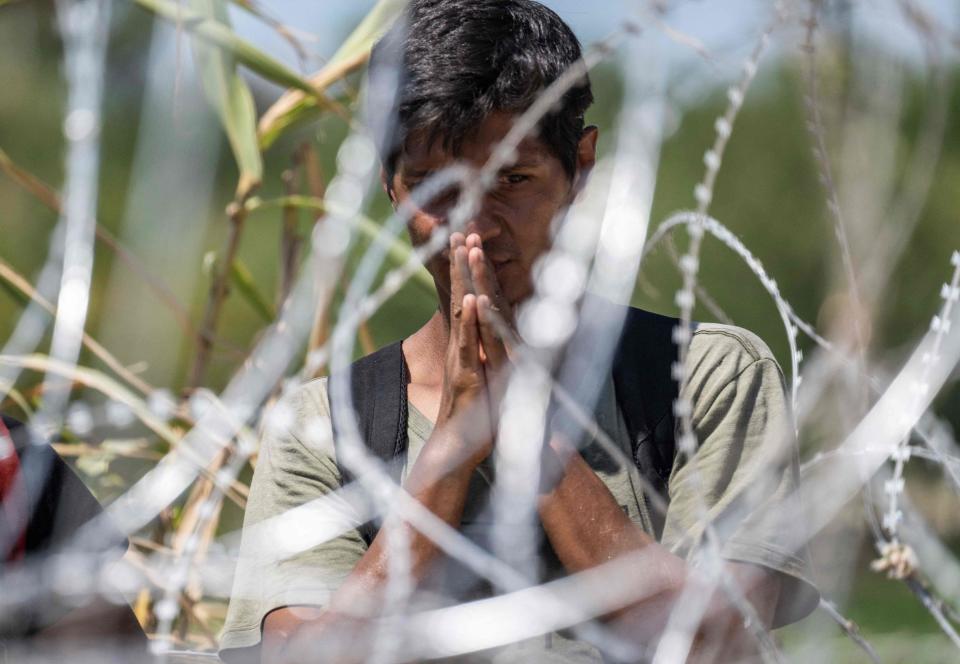 September 24, 2023: A migrant from Venezuela prays as he waits for US Border Patrol agents to cut the razor wire after he crossed the Rio Grande to Eagle Pass, Texas. Dozens of migrants arrived at the US-Mexico border September 22, hoping to be allowed into the United States, with US border forces reporting 1.8 million encounters with migrants in the last 12 months.