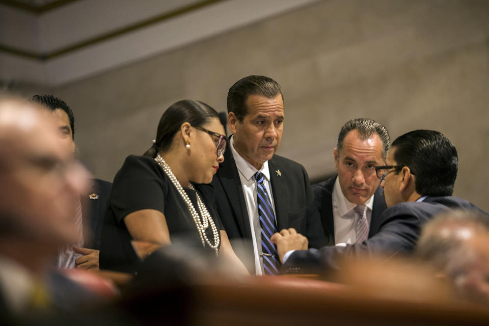 President of the Pedro Pierluisi confirmation hearing, lawmaker Georgie Navarro, center, talks to other representatives before the hearing, at the House of Representatives, in San Juan, Puerto Rico, Friday, August 2, 2019. As Gov. Ricardo Rossello is expected to leave office in a few hours, the Puerto Rican House of Representatives is expected to vote on Pierluisi's confirmation Friday afternoon. If he is rejected, Justice Secretary Wanda Vazquez automatically becomes governor as the next in the order of succession, even though she has said she would unwillingly accept the job. (AP Photo/Dennis M. Rivera Pichardo)