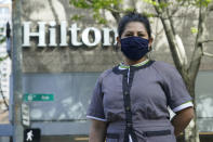 Sonia Guevara poses for a photo, Wednesday, May 18, 2022, outside the Hilton hotel where she works as a housekeeper in downtown Seattle. Many hotels across the United States have done away with daily housekeeping service, making what was already one of the toughest jobs in the hospitality industry even more grueling. (AP Photo/Ted S. Warren)