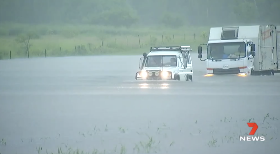 Cars pictured driving through floodwaters in North Queensland.