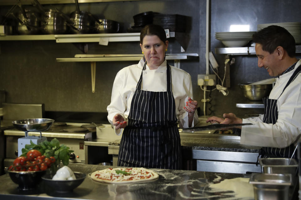 Britain's Liberal Democrats leader Jo Swinson learns how to make a pizza with Italian chef Leonardo Mastrofilippo in Cafe Amisha as she campaigns in the Southwark and Old Bermondsey constituency in south London, Saturday, Nov. 16, 2019. (AP Photo/Matt Dunham)