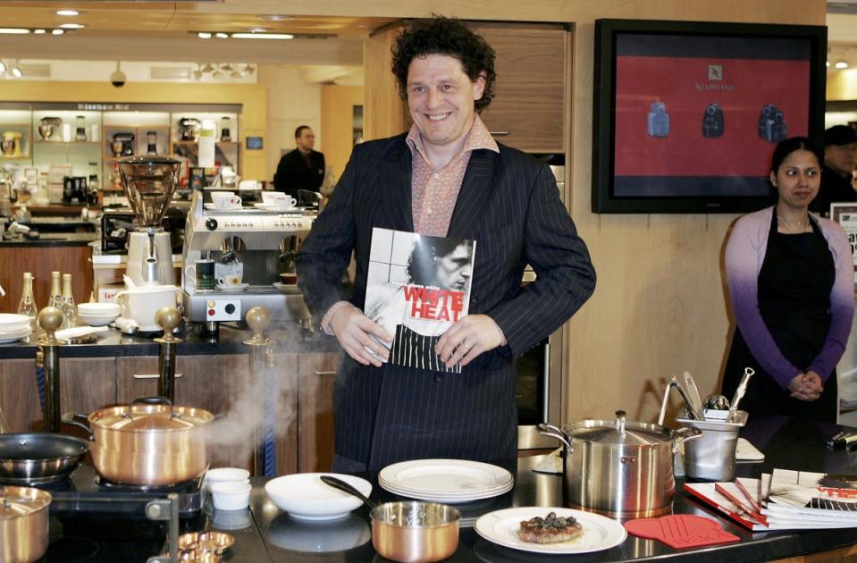 Marco Pierre White poses during the launch of his cookware, The White Heat Collection, with a copy of his book ‘White Heat’, on 8 April 2006 at Harrods in London, England (MJ Kim/Getty Images)