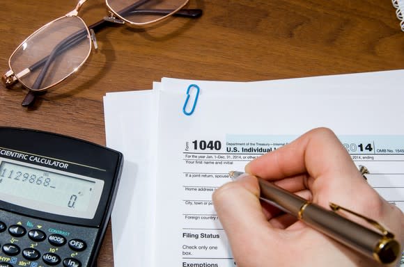 A person holding a pen while filling out tax forms