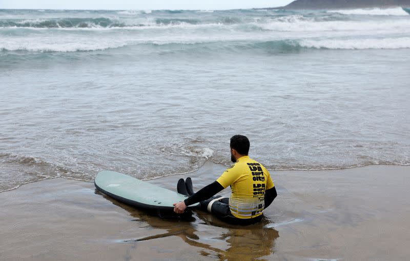 Surfer David Fernandez, who suffered an accident which left him having to use a wheelchair a year ago, prepares to enter the water during an adaptive surfing championship in Las Palmas de Gran Canaria