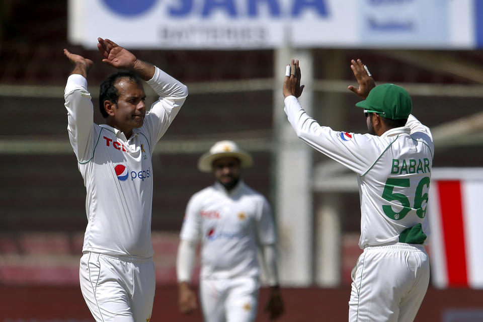 Pakistan's Nauman Ali, left, celebrates with teammate Babar Azam after taking the wicket of Australia's Cameron Green during the second day of the second test match between Pakistan and Australia at the National Stadium, in Karachi, Pakistan, Sunday, March 13, 2022. (AP Photo/Anjum Naveed)