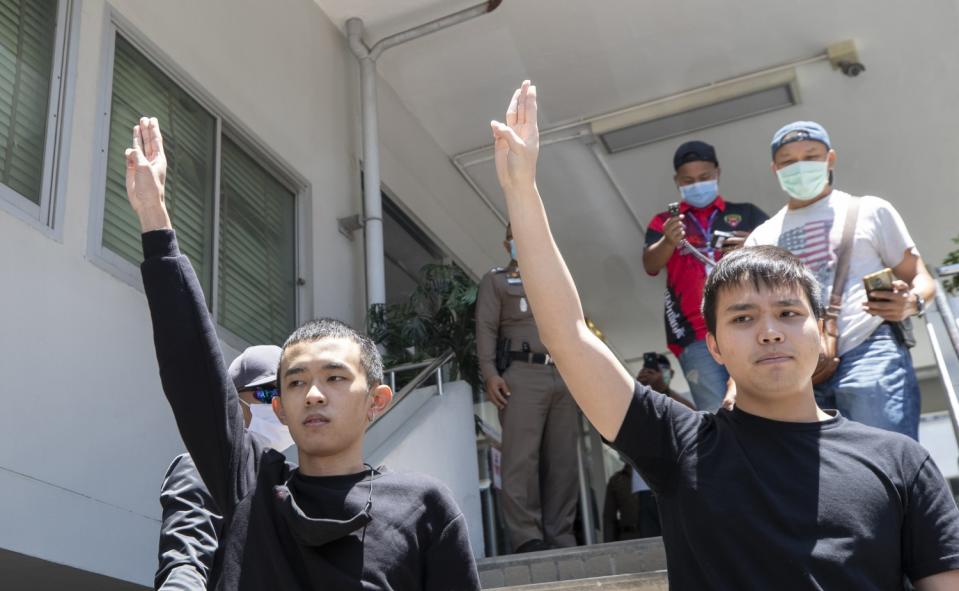 Panumas Singprom, left, and Tattep Ruangprapaikitseree raise a three-finger salute at the police station in Bangkok.