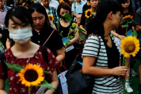 Pro-democracy activists hold sunflowers to attend a public memorial for anti-extradition bill protester Marco Leung, who died after falling from a scaffolding at the Pacific Place complex while protesting, in Hong Kong