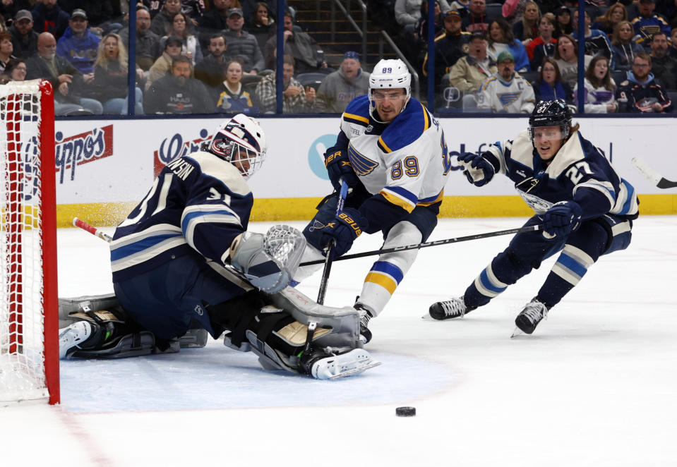 Columbus Blue Jackets goalie Michael Hutchinson, left, makes a stop in front of St. Louis Blues forward Pavel Buchnevich, center, and Blue Jackets defenseman Adam Boqvist during the first period of an NHL hockey game in Columbus, Ohio, Saturday, March 11, 2023. (AP Photo/Paul Vernon)