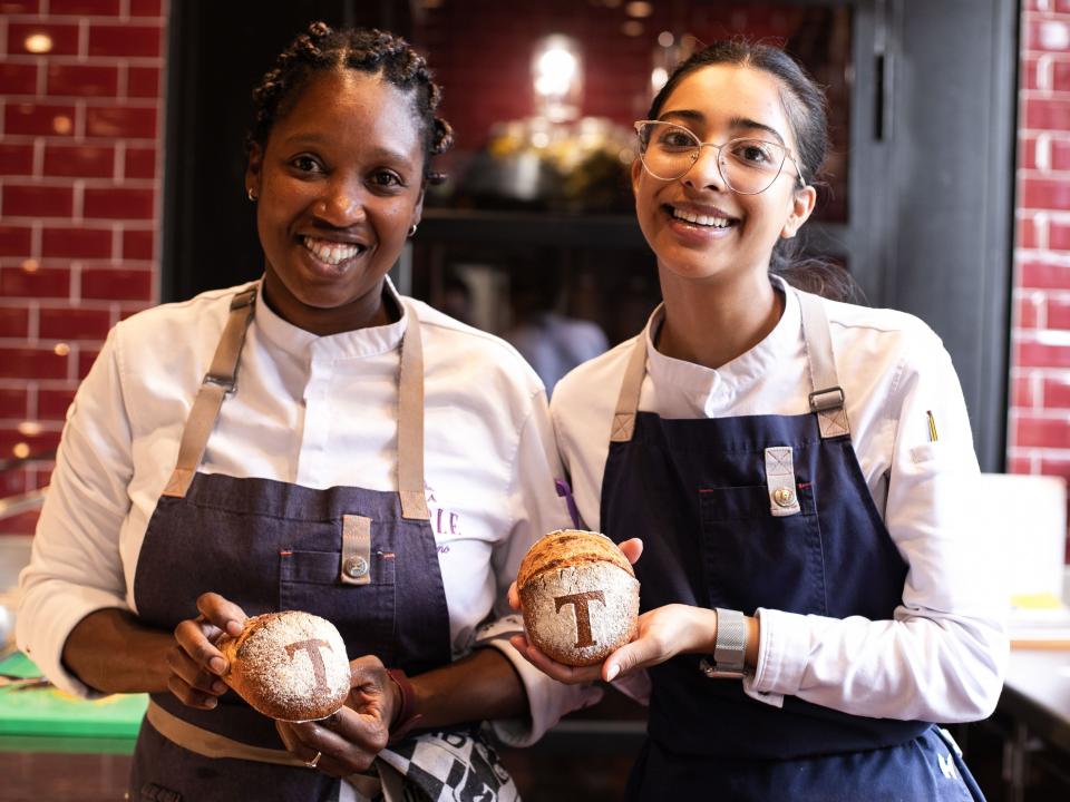 The writer and another pastry chef hold up bread rolls