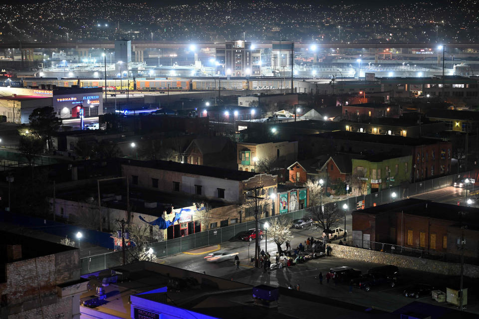 Lights from Ciudad Juarez, Mexico glow on the horizon as migrants camp out at night in freezing temperatures in downtown El Paso near a bus station while waiting for transportation to shelter after crossing the border to seek asylum in El Paso, Texas. (Patrick T. Fallon / AFP - Getty Images)