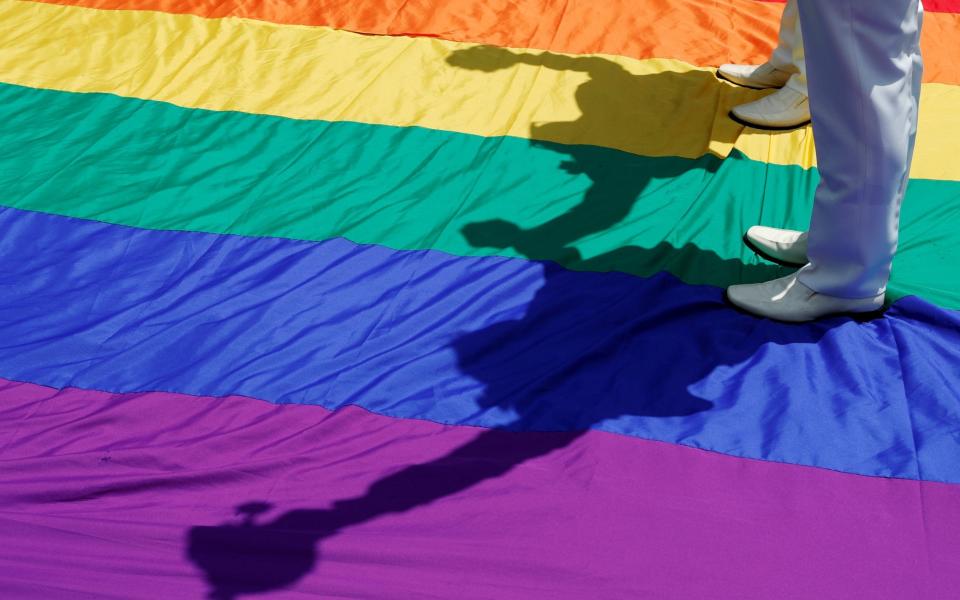 Gay newlyweds walk on a giant rainbow flag at a pro same-sex marriage part in Taiwan - REUTERS