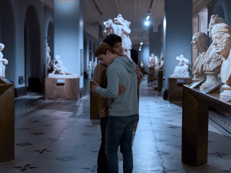 alex and henry in red white and royal blue, dancing together and embracing in a museum filled with statues and busts